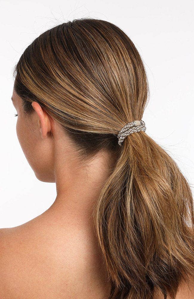 Woman with a high ponytail held by a decorative hair tie against a white background
