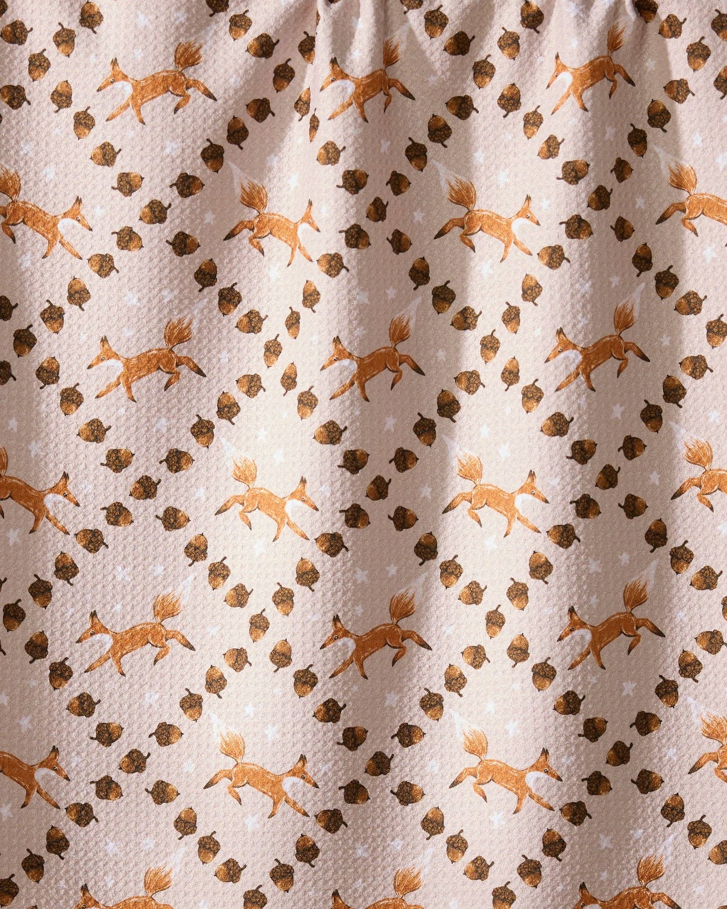 Patterned fabric with small foxes and leaf design on a beige background