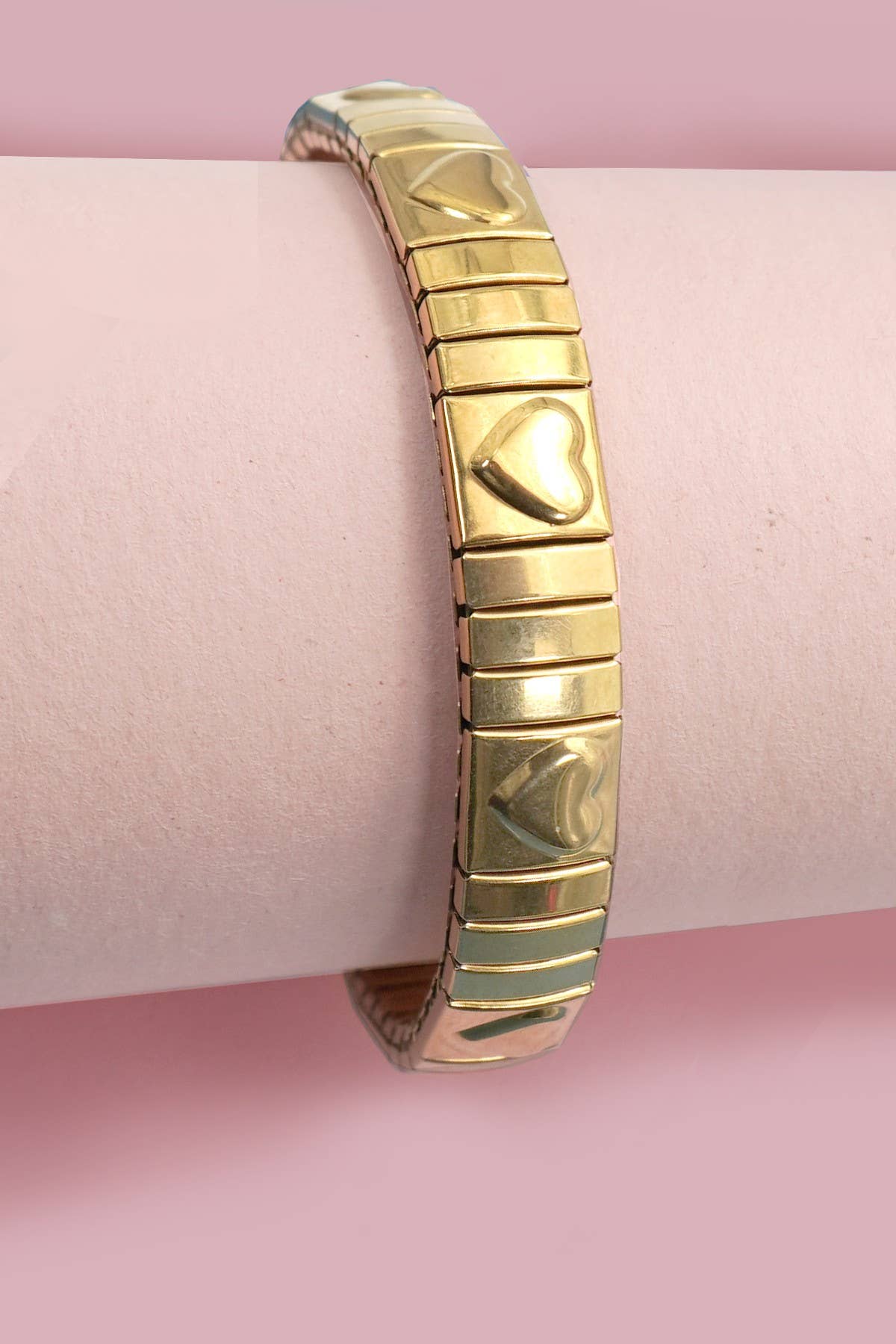 Gold bracelet on a pink surface