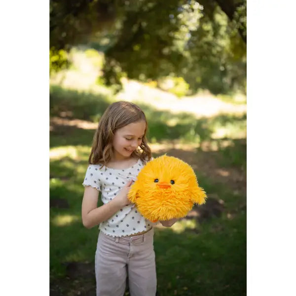 Young girl holding a fluffy yellow toy in a park