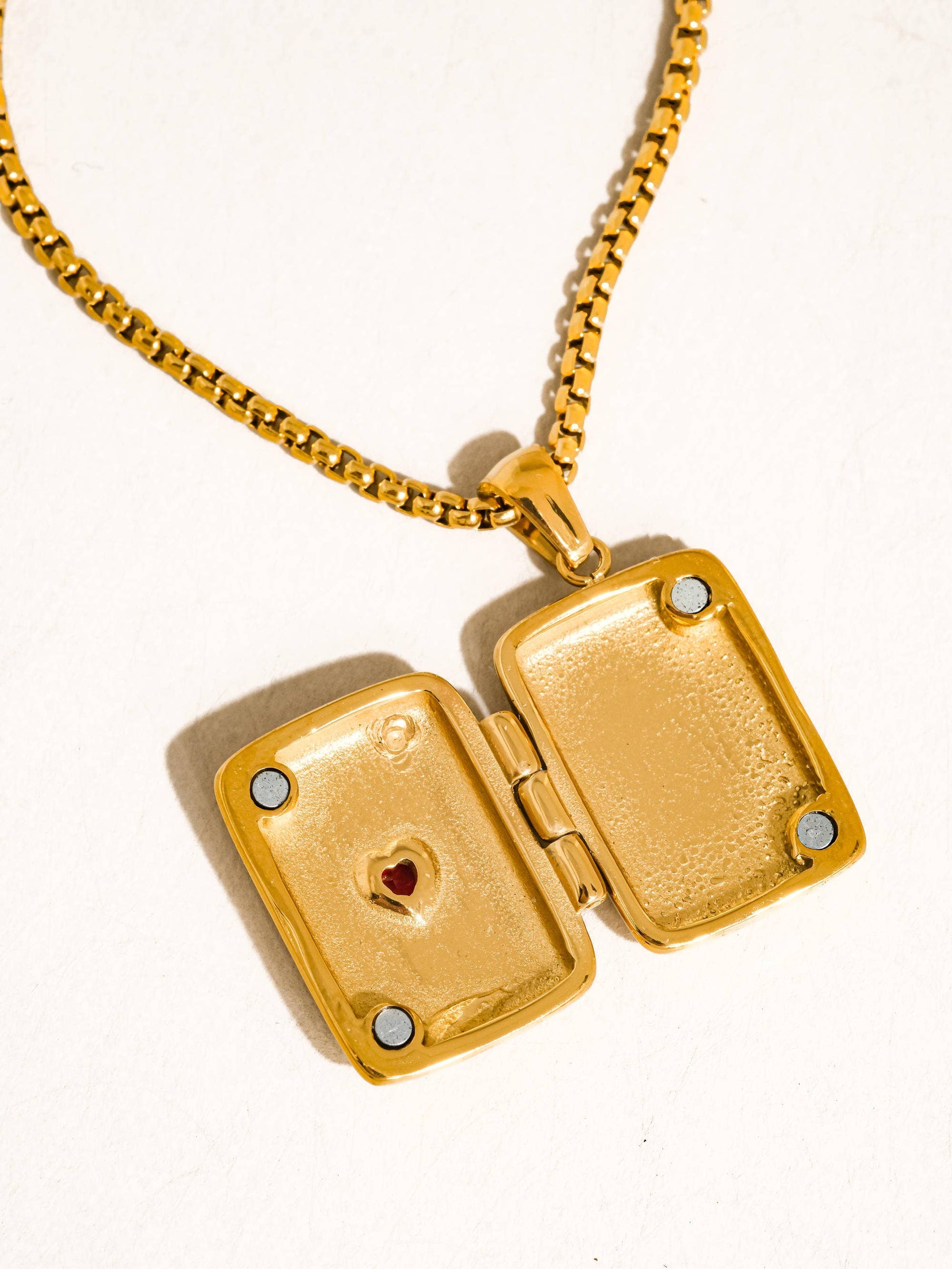 Gold locket necklace with a heart design on a white background