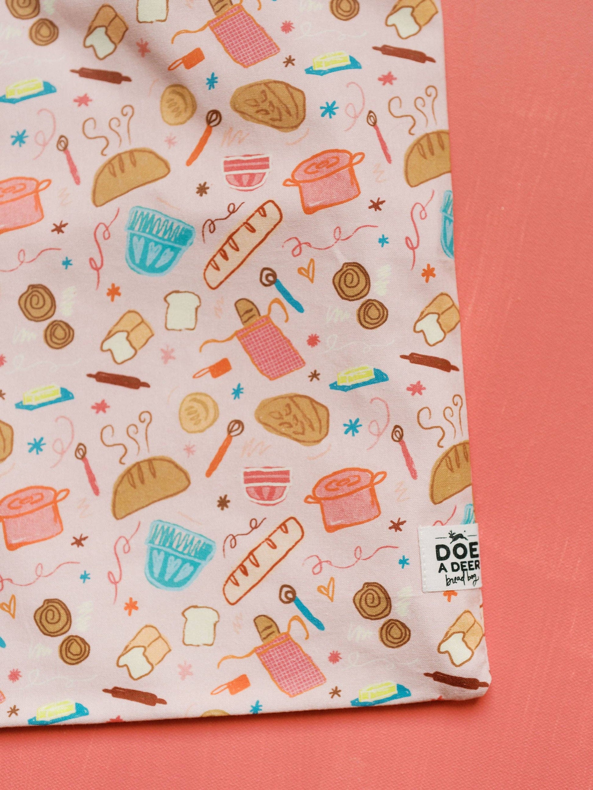 Fabric with bread and kitchen utensil pattern on a pink background