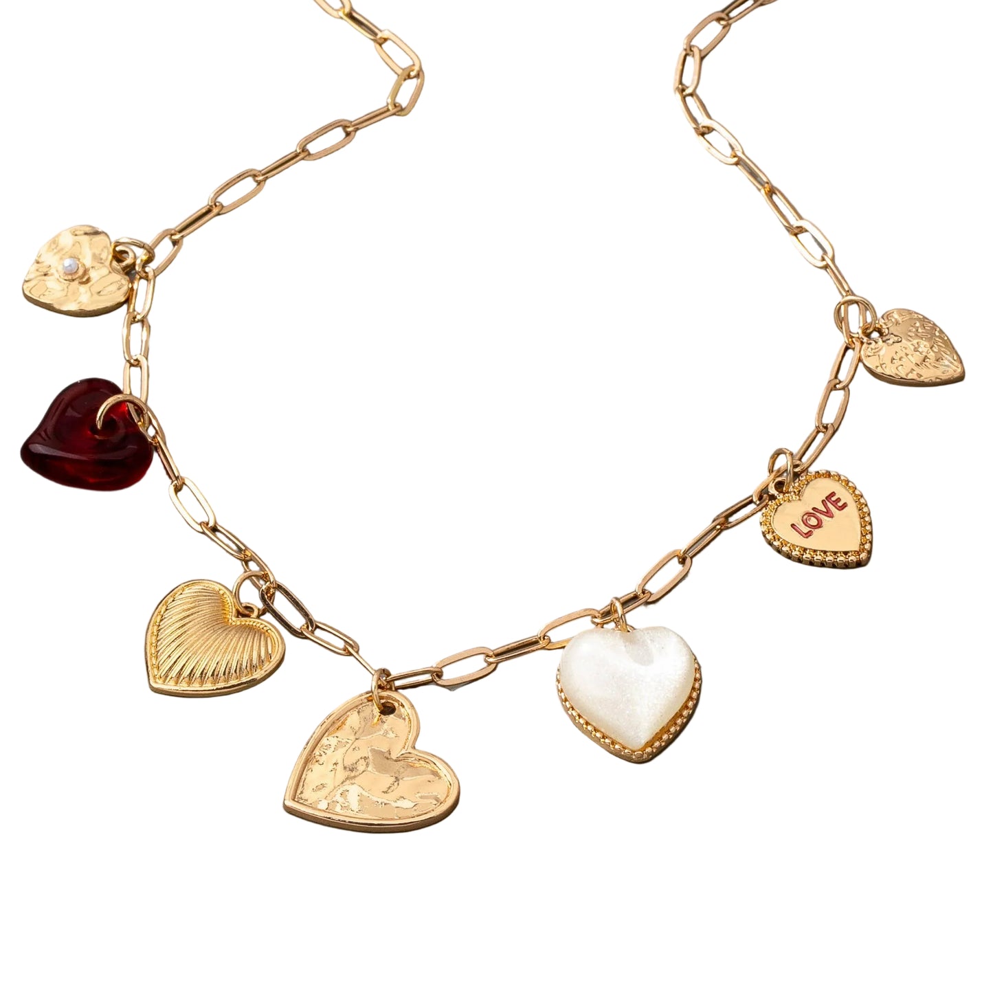 Gold chain link necklace with 5 different heart shaped gold charms, 1 pearl heart charm, and one clear red charm, on a white background
