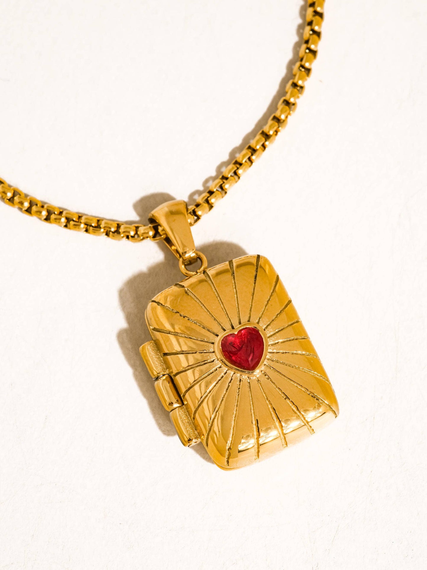 Gold pendant with a red heart on a white background