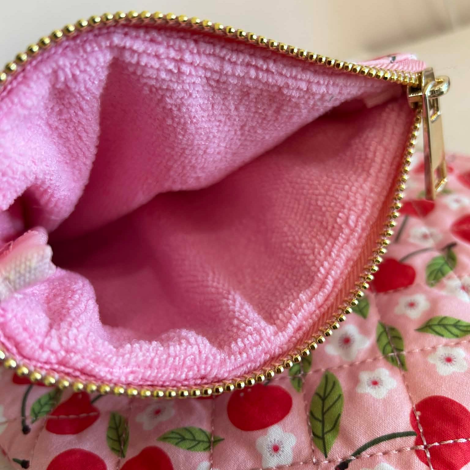 Close-up of a pink fabric pouch with a floral pattern and gold zipper.
