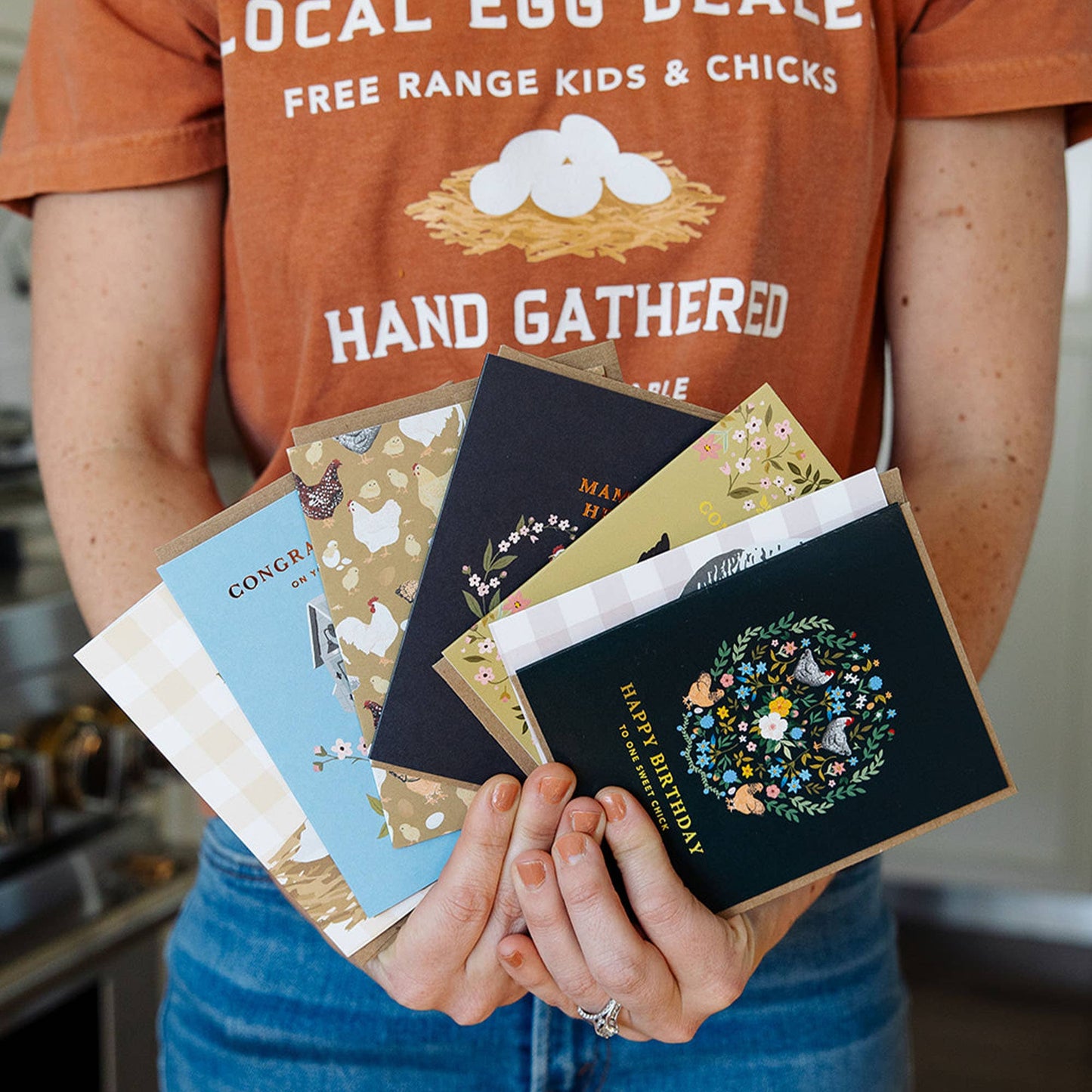 Person holding a collection of greeting cards with a focus on design and text.