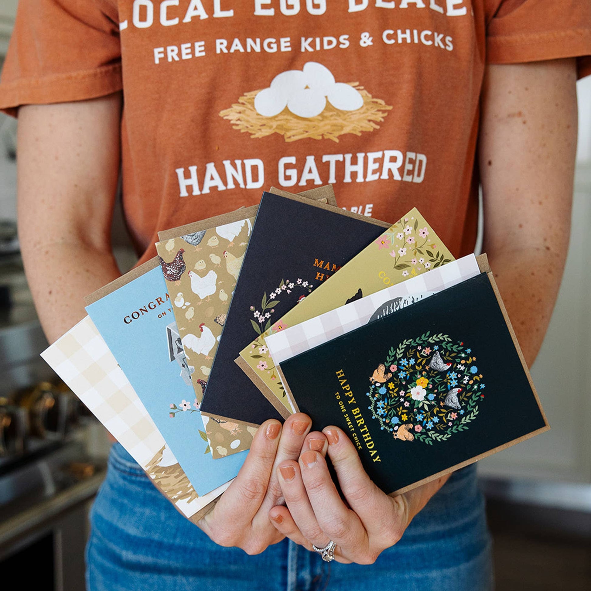 Person holding a collection of greeting cards with a focus on design and text.