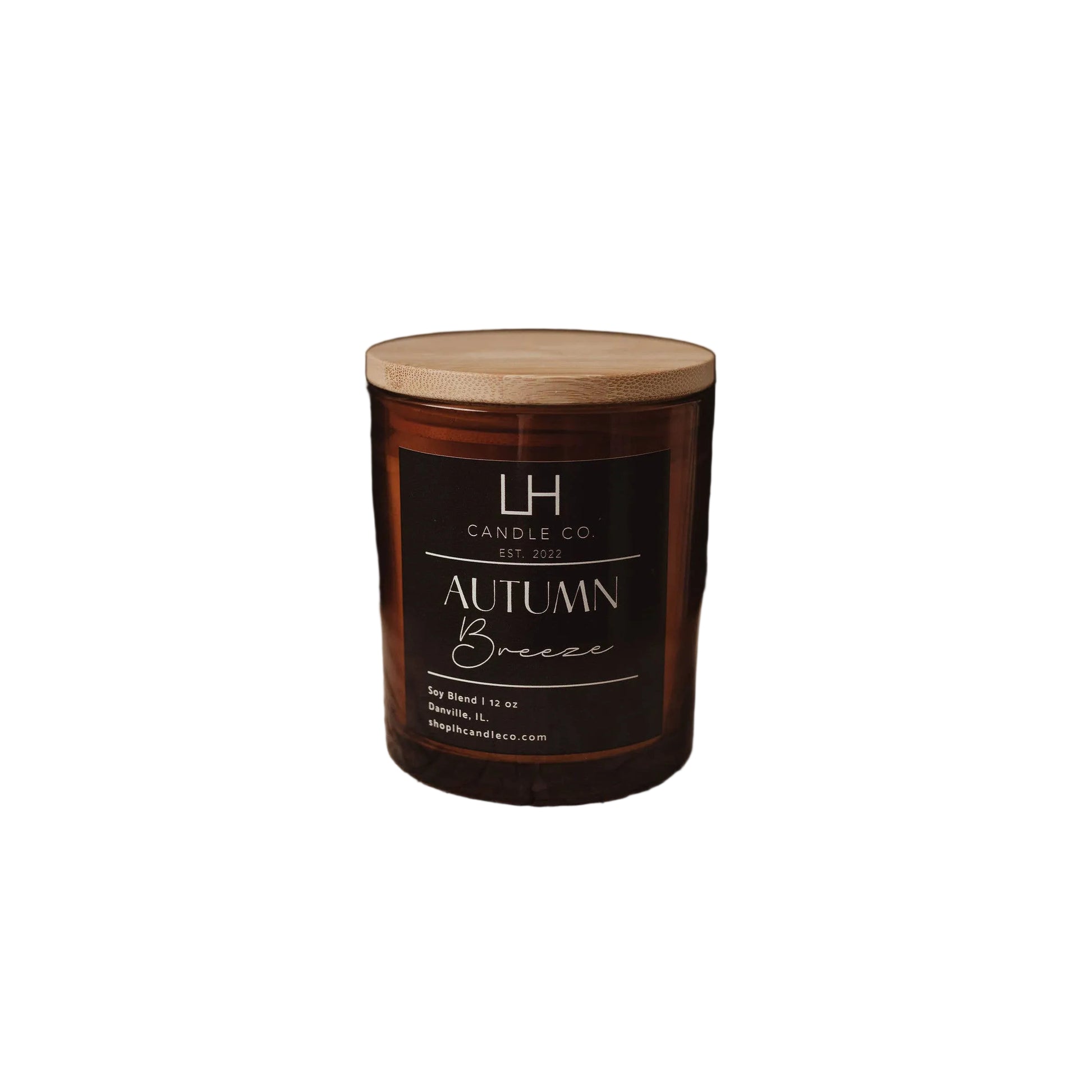 An amber glass jar candle with a light wood lid sits on white background. The front label reads 'LH Candle Co' and 'Autumn Breeze'.