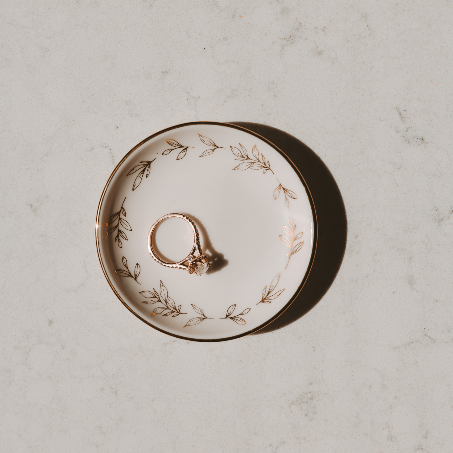 Ring on a decorative plate with floral patterns on a light gray surface