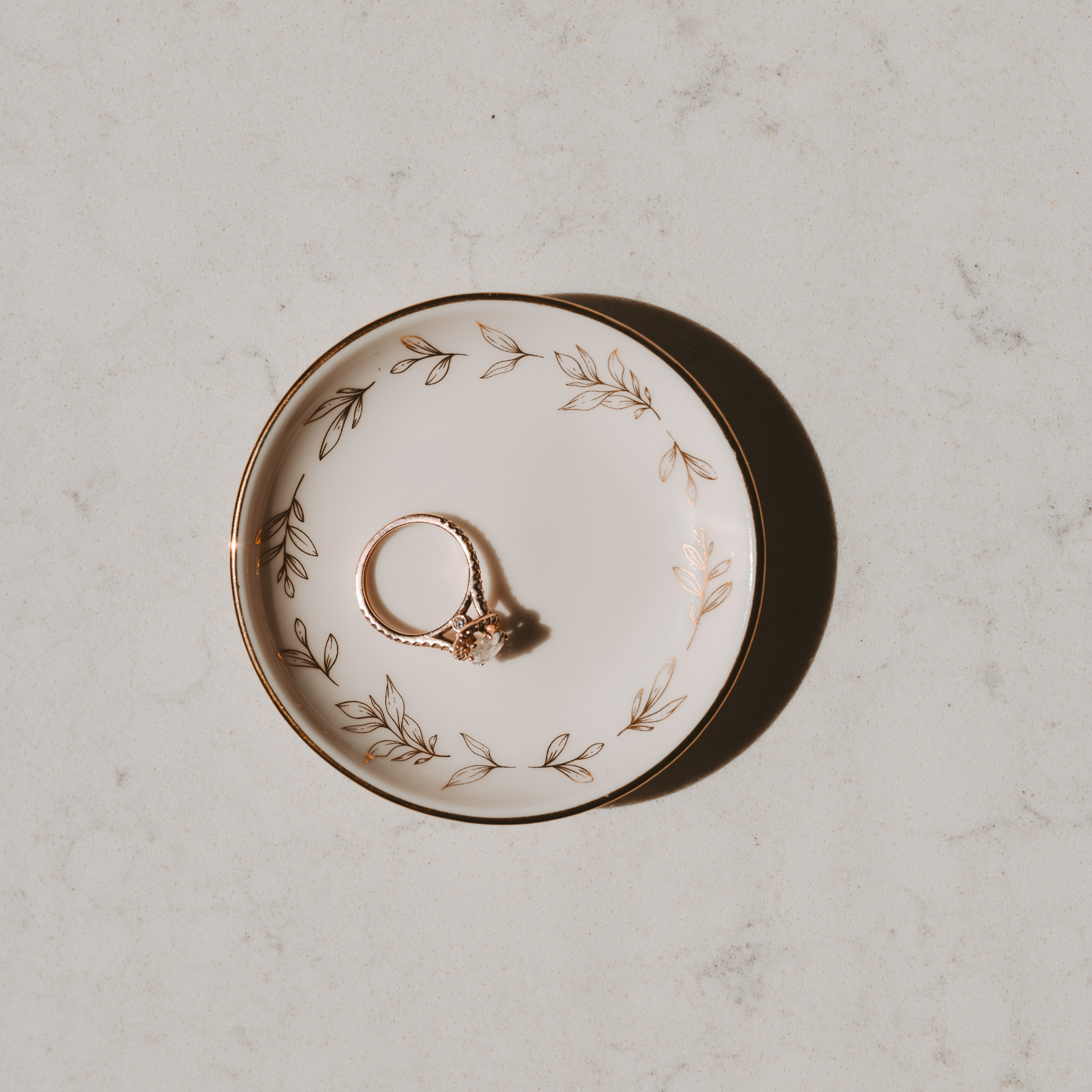 Ring on a decorative plate with floral patterns on a light gray surface