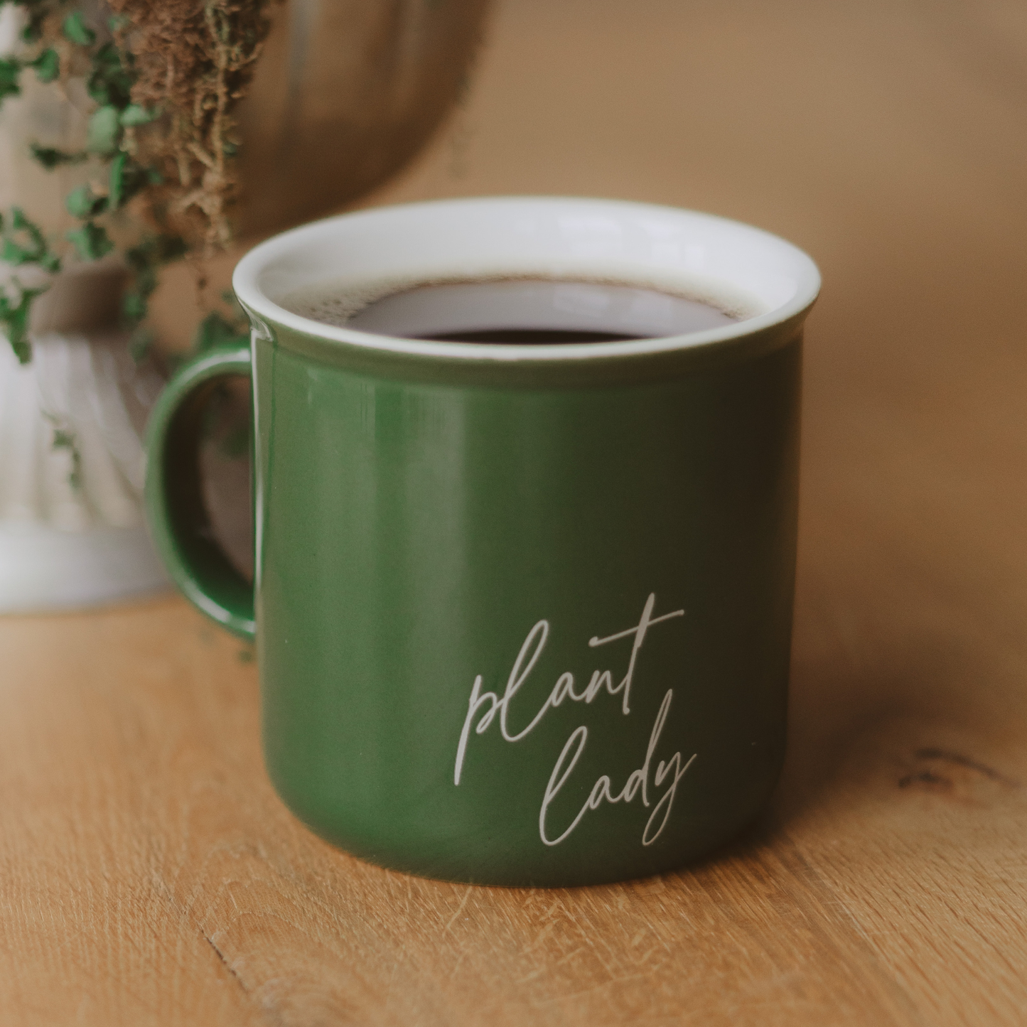 Green mug with 'plant lady' text on a wooden surface