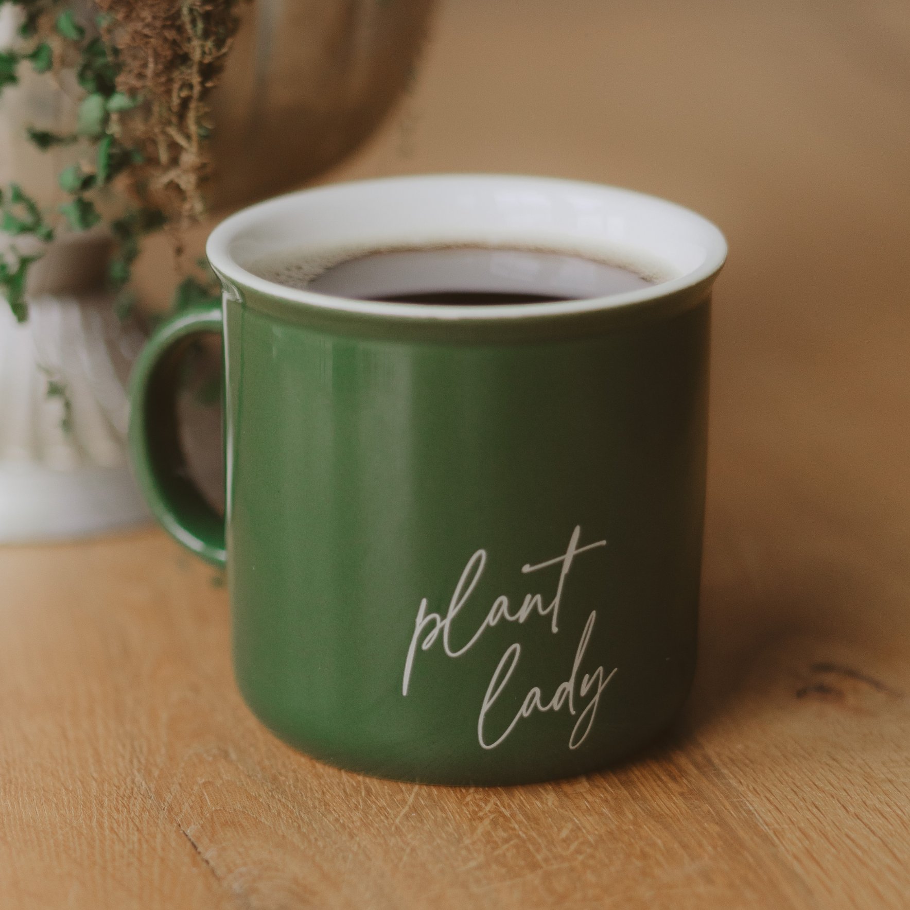 Green mug with 'plant lady' text on a wooden surface