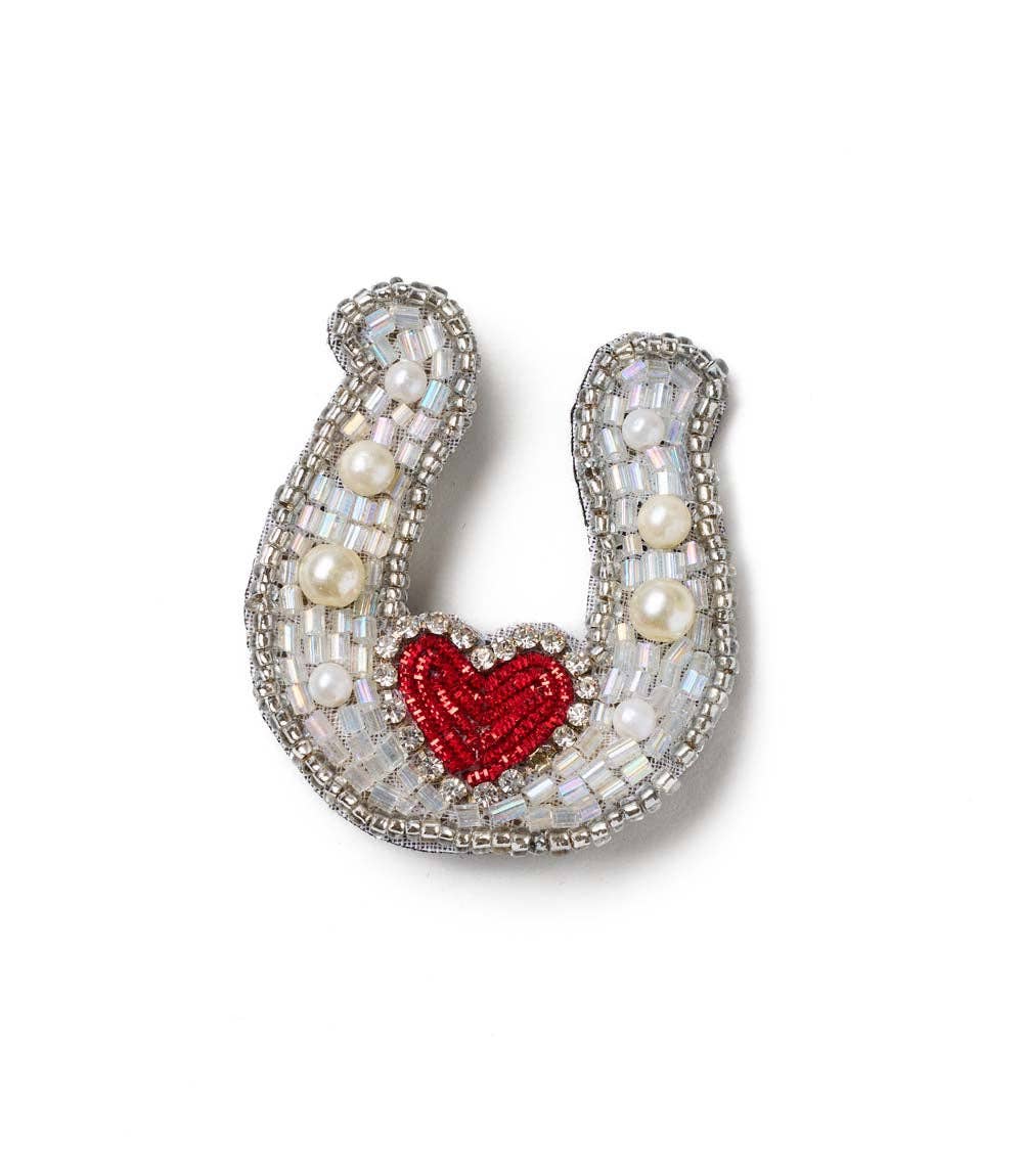 Decorative horseshoe with a red heart and pearl embellishments on a white background