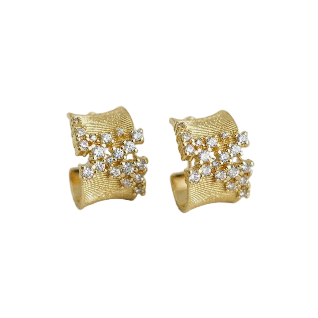 Gold earrings with diamond-like stones on a light gray background