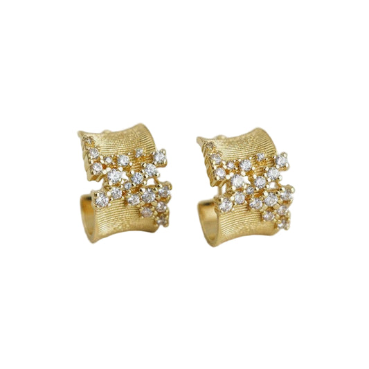 Gold earrings with diamond-like stones on a light gray background