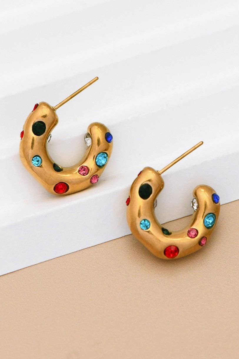 Gold hoop earrings with colorful gemstones on a white and beige background