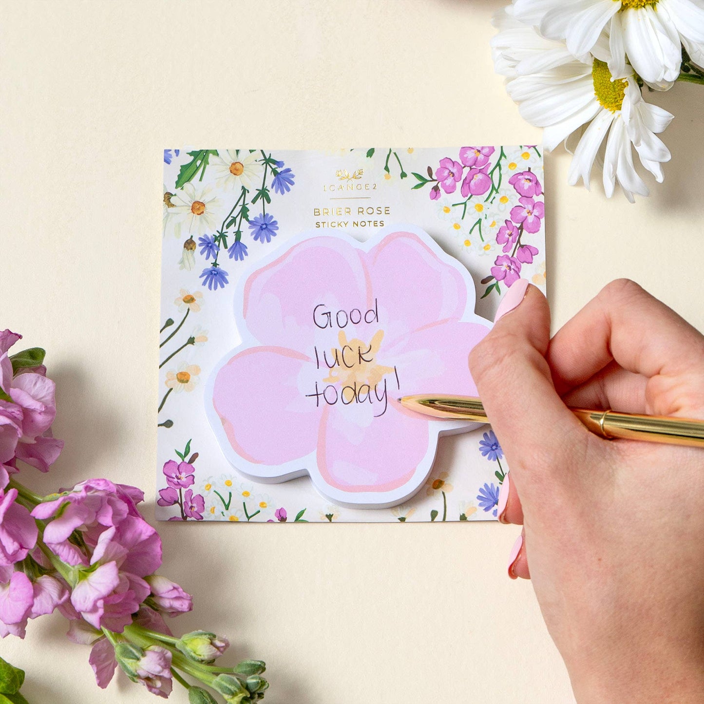 Floral-themed sticky notes with a hand holding a pen and flowers on a light background