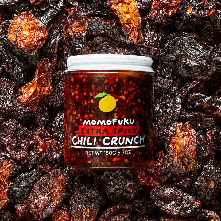 Jar of Momofuku Extra Spicy Chili Crunch surrounded by dried chili peppers