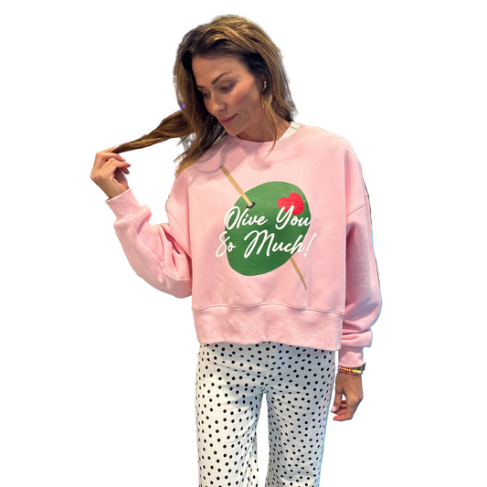 Woman wearing a pink sweatshirt with a green graphic and text in a store setting