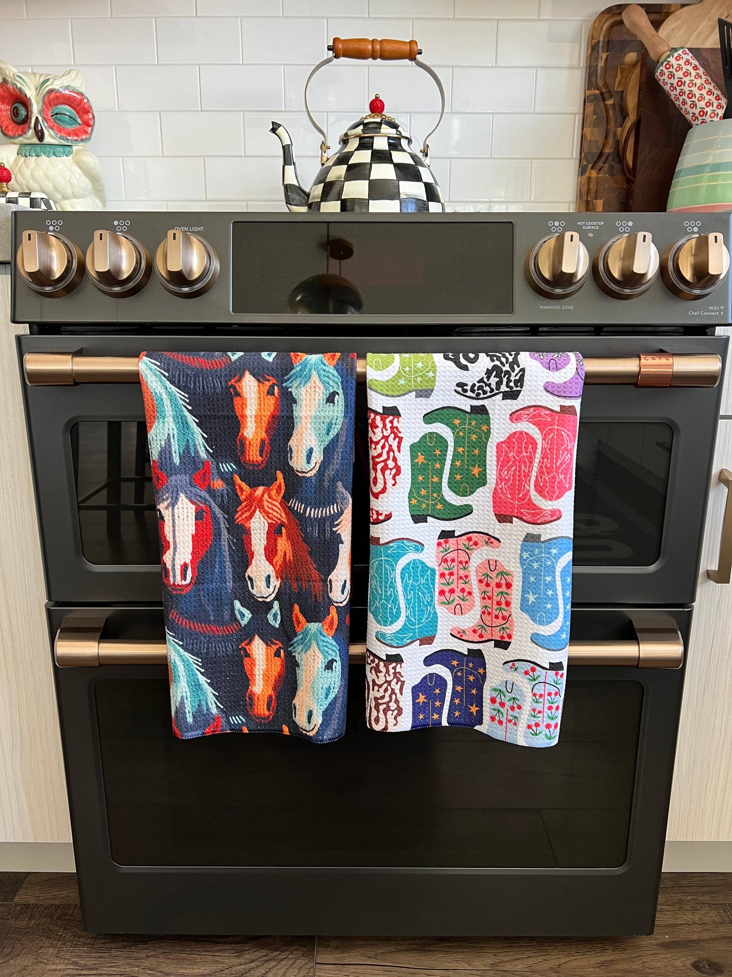 Colorful horse-patterned tea towel hanging on a kitchen stove.