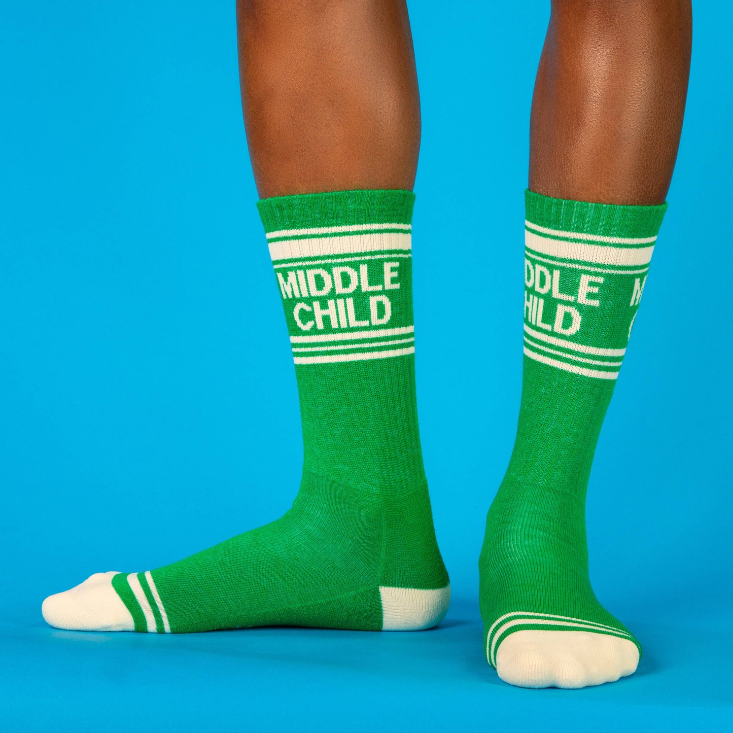 Green socks with 'Middle Child' text worn by a person on a blue background
