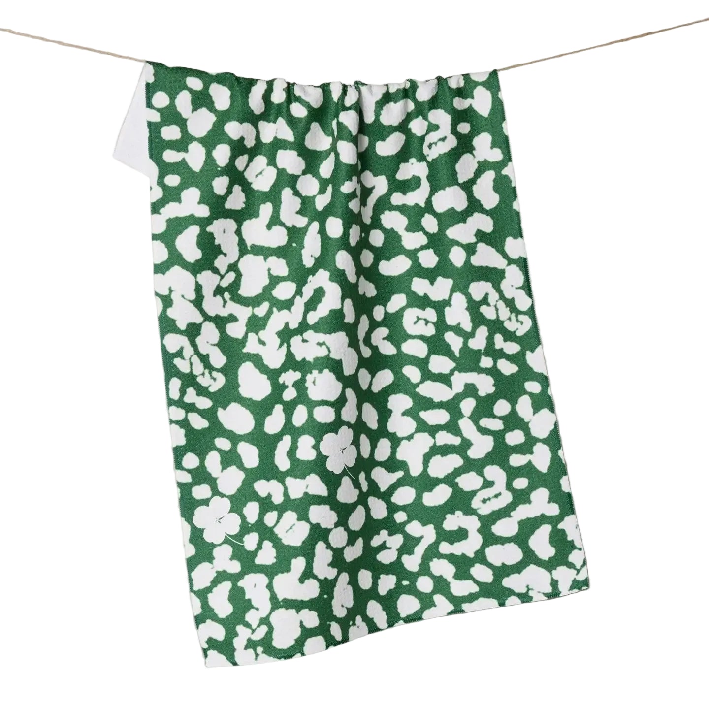 Green towel with white pattern hanging on a line against a neutral background