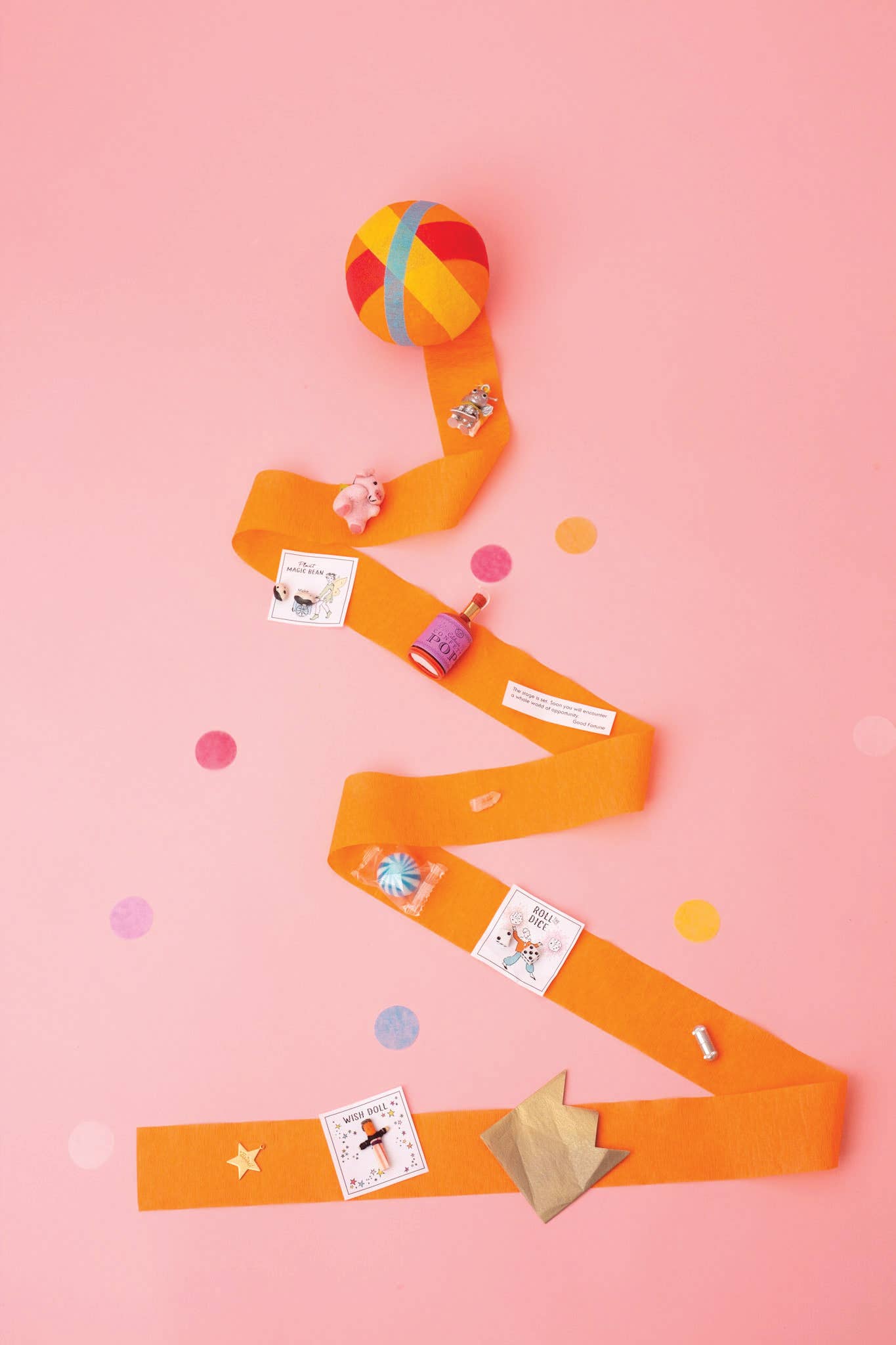 Colorful toy snake with small toys attached on a pink background