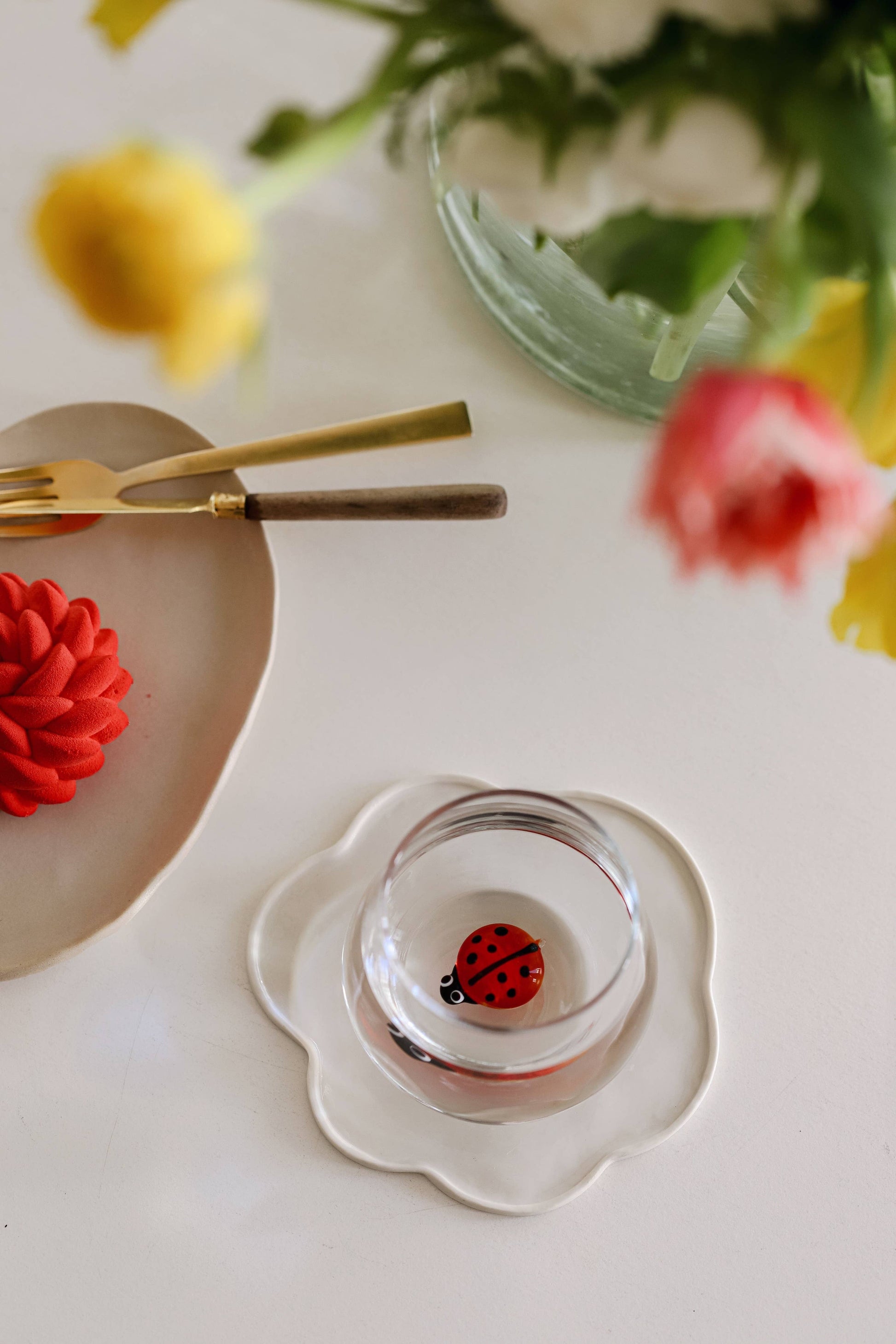 glass with small lady bug figurine in the center of it sitting on a white tray