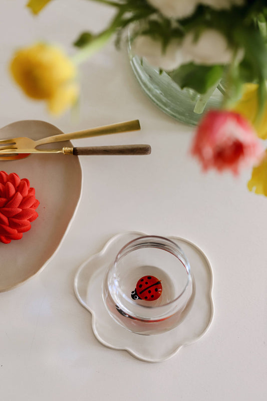 glass with small lady bug figurine in the center of it sitting on a white tray