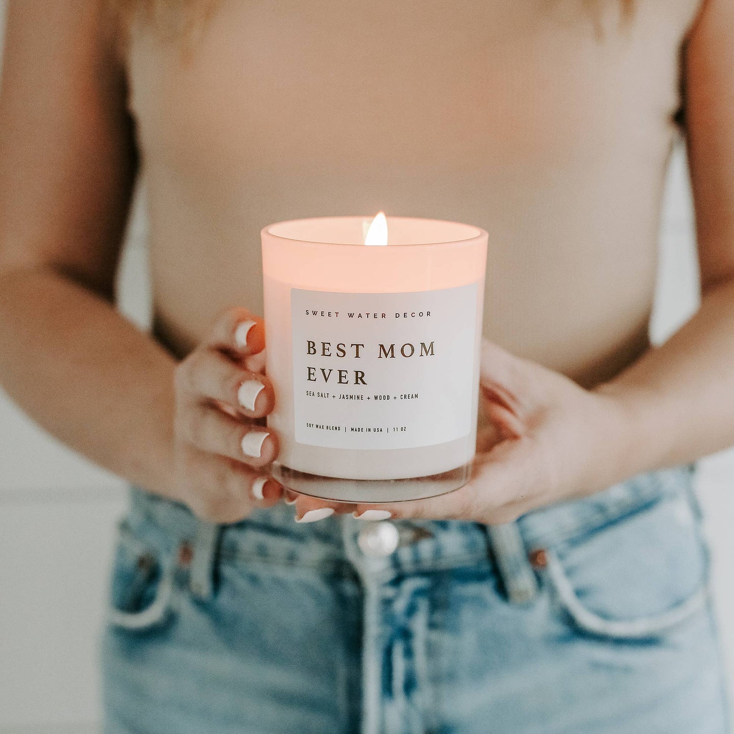 Person holding a candle labeled 'Best Mom Ever' with a soft focus background