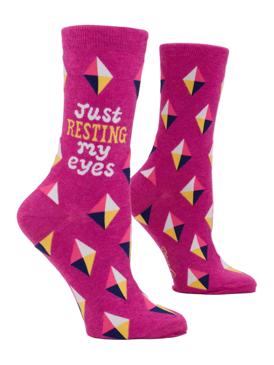 Pink socks with geometric pattern and text 'Just Resting My Eyes' on a white background