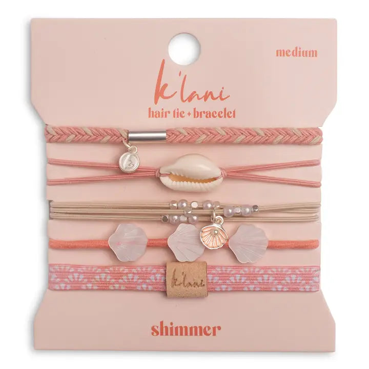 Packaged hair tie and bracelet set with shell and heart charms on a pink background