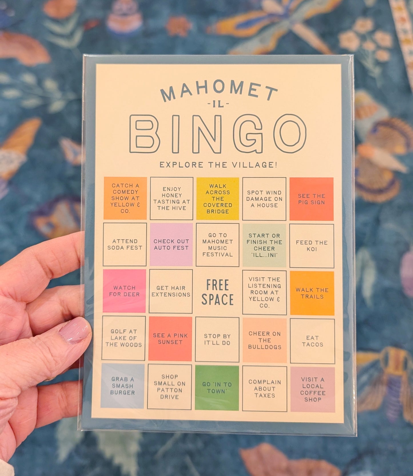 Bingo card titled 'Mahomet Bingo' held by a hand with a colorful background