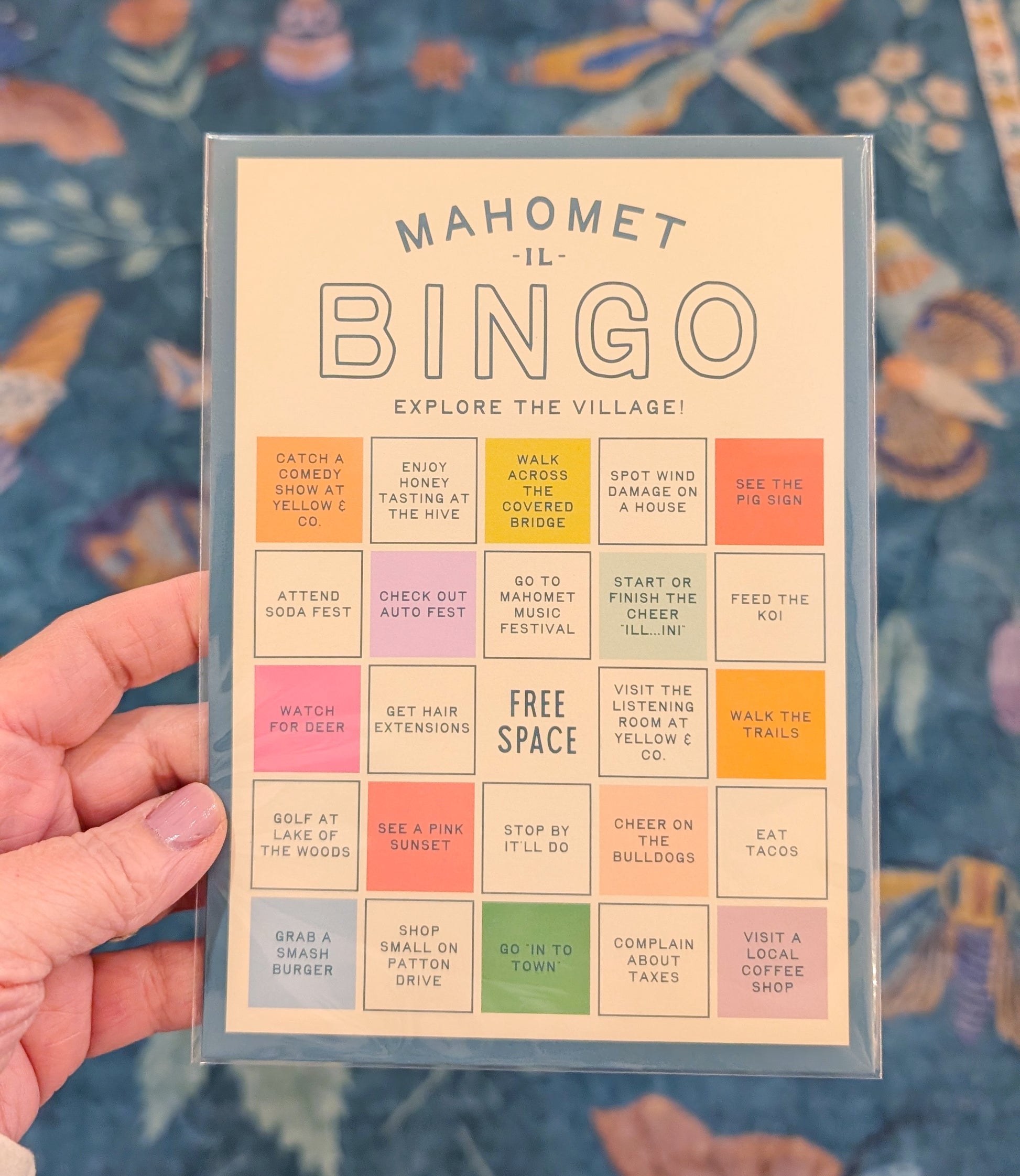 Bingo card titled 'Mahomet Bingo' held by a hand with a colorful background
