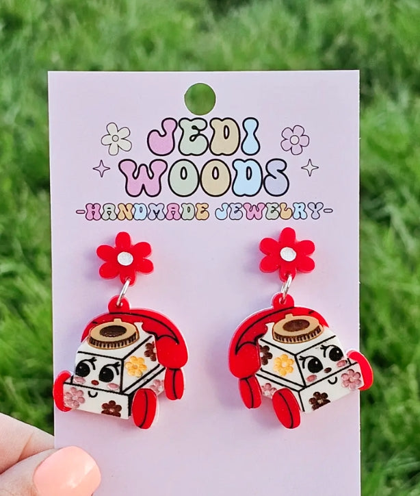 Earrings with cartoonish design on a 'Jedi Woods Handmade Jewelry' card against a grass background.
