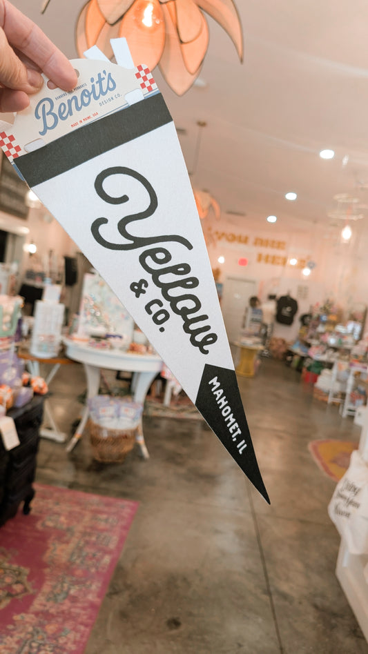 Hand holding a 'Benoit's Yellow Co.' branded flag inside a store.