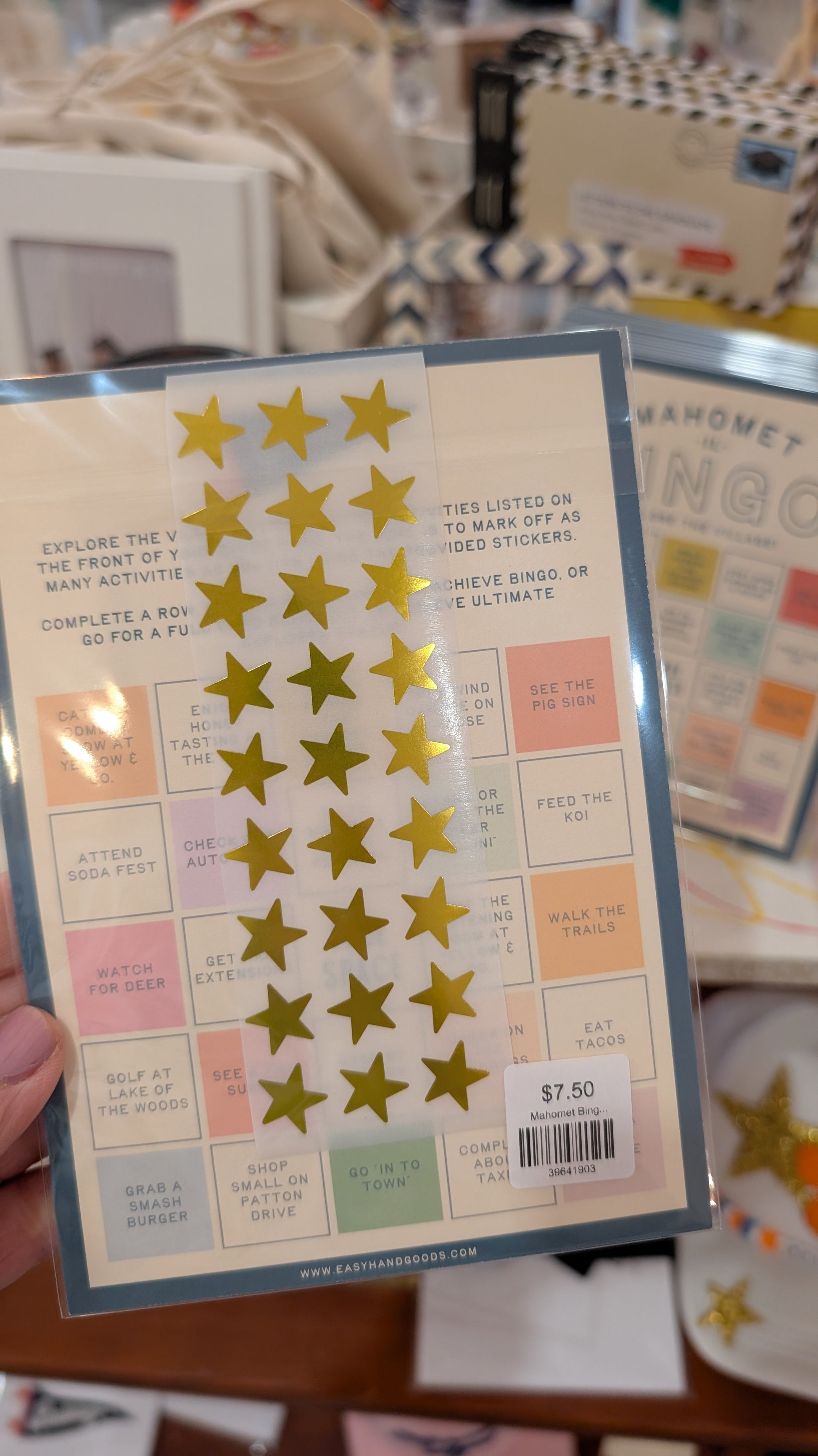 Pack of gold star stickers with a colorful label held by a hand.