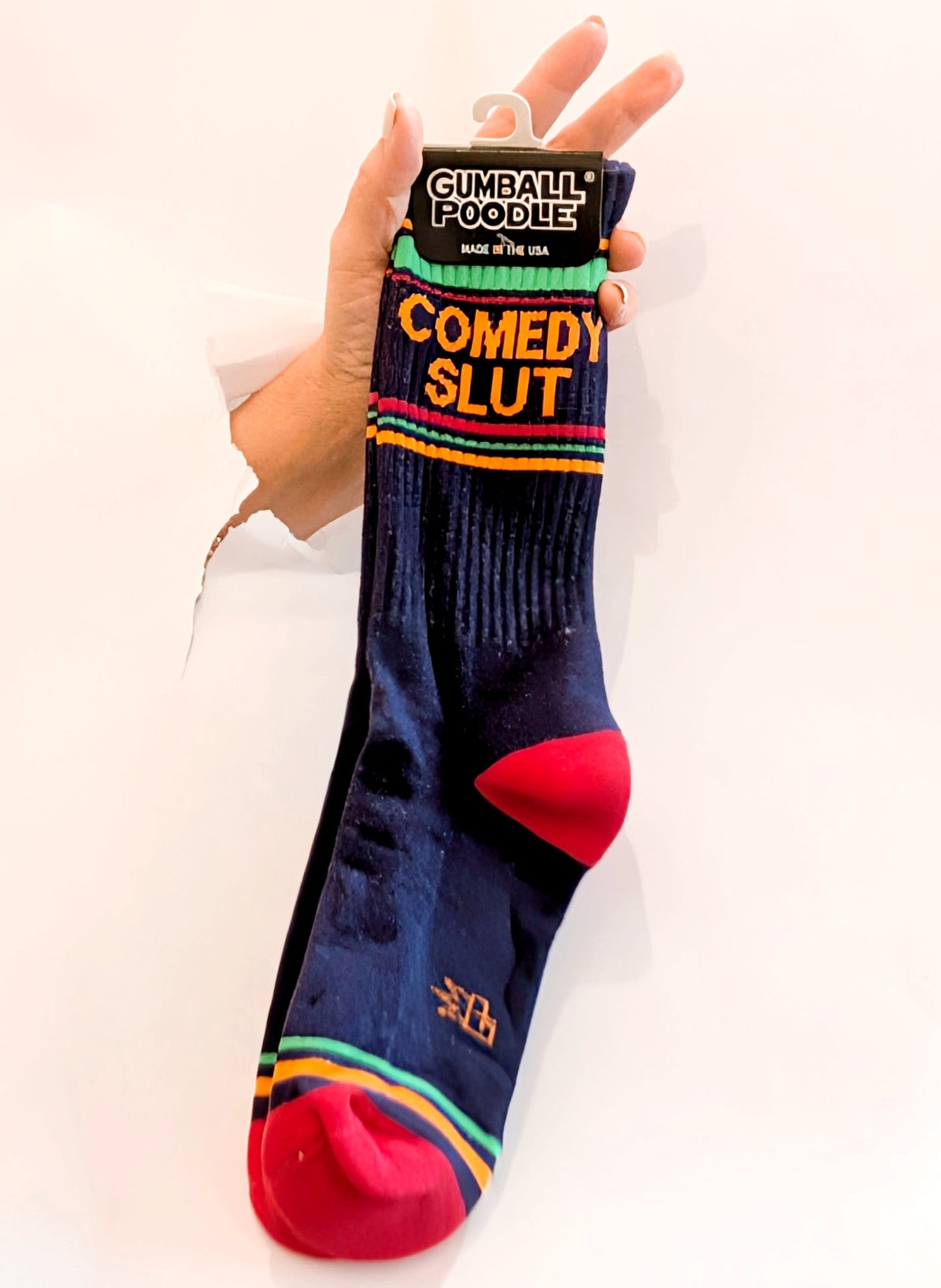 Sock with 'Comedy Slut' text held by a hand against a white background