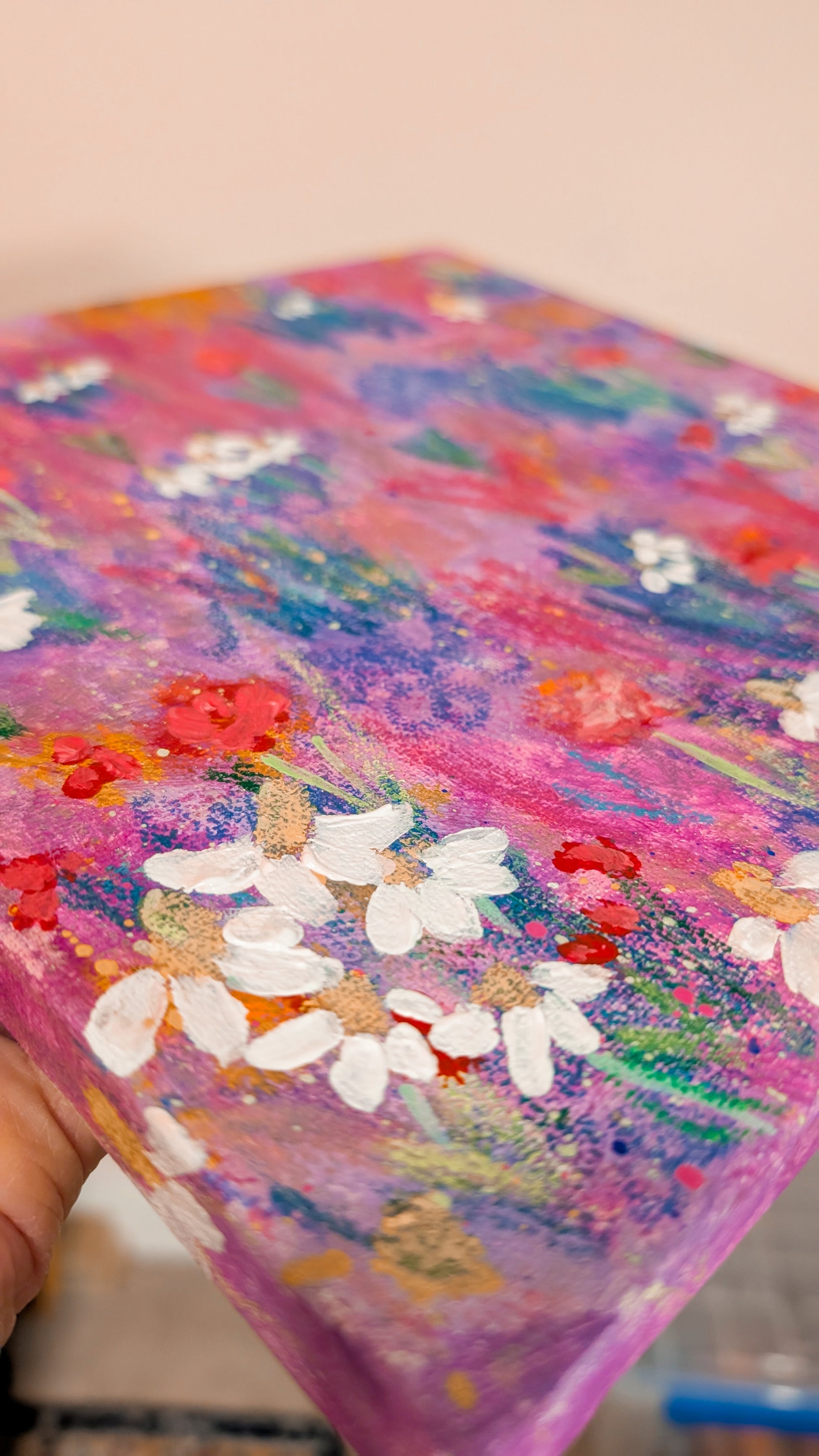 Painting of flowers in a field with white, red, orange, pink, and purple.