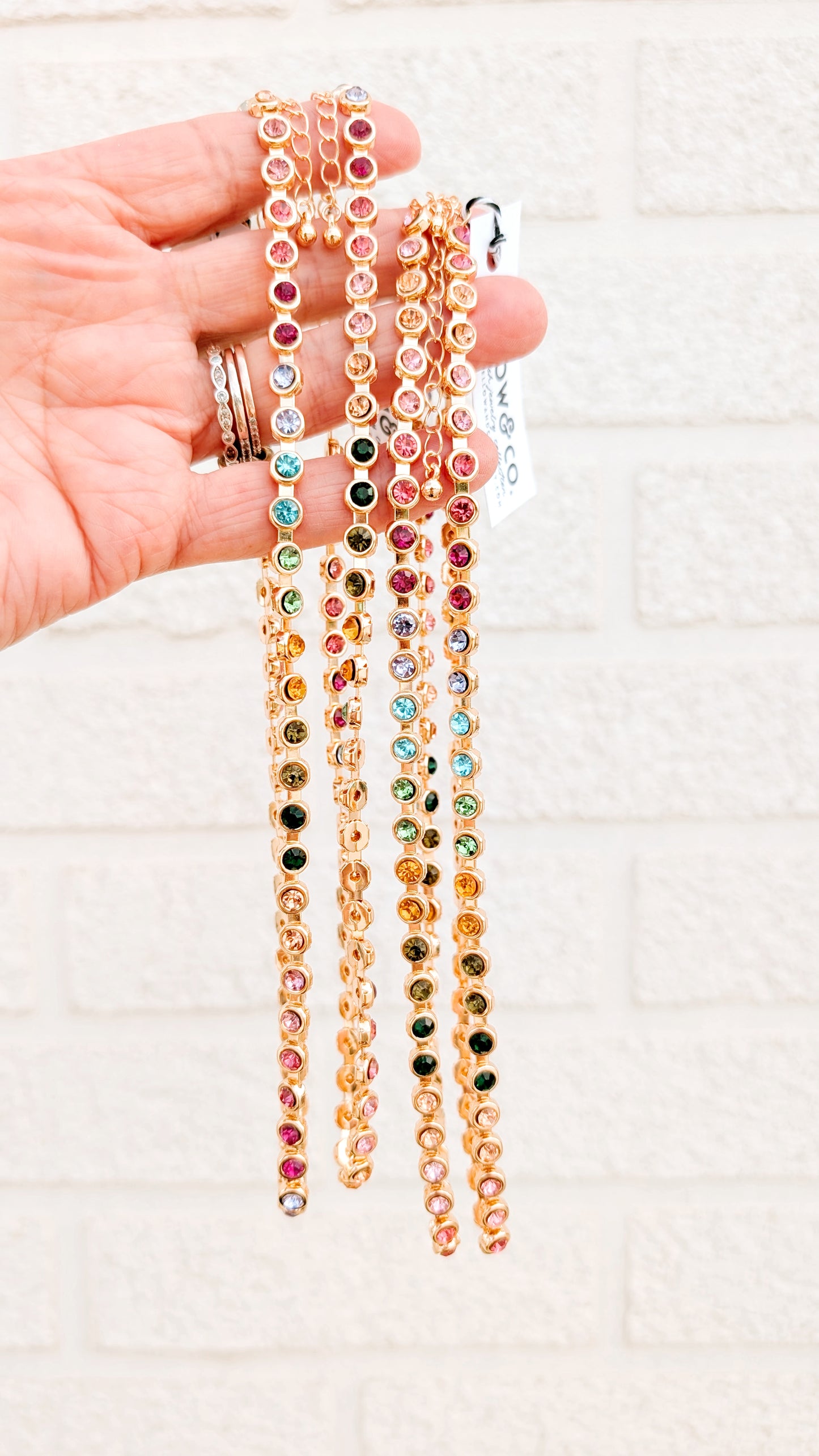 Hand holding colorful beaded necklaces against a white background