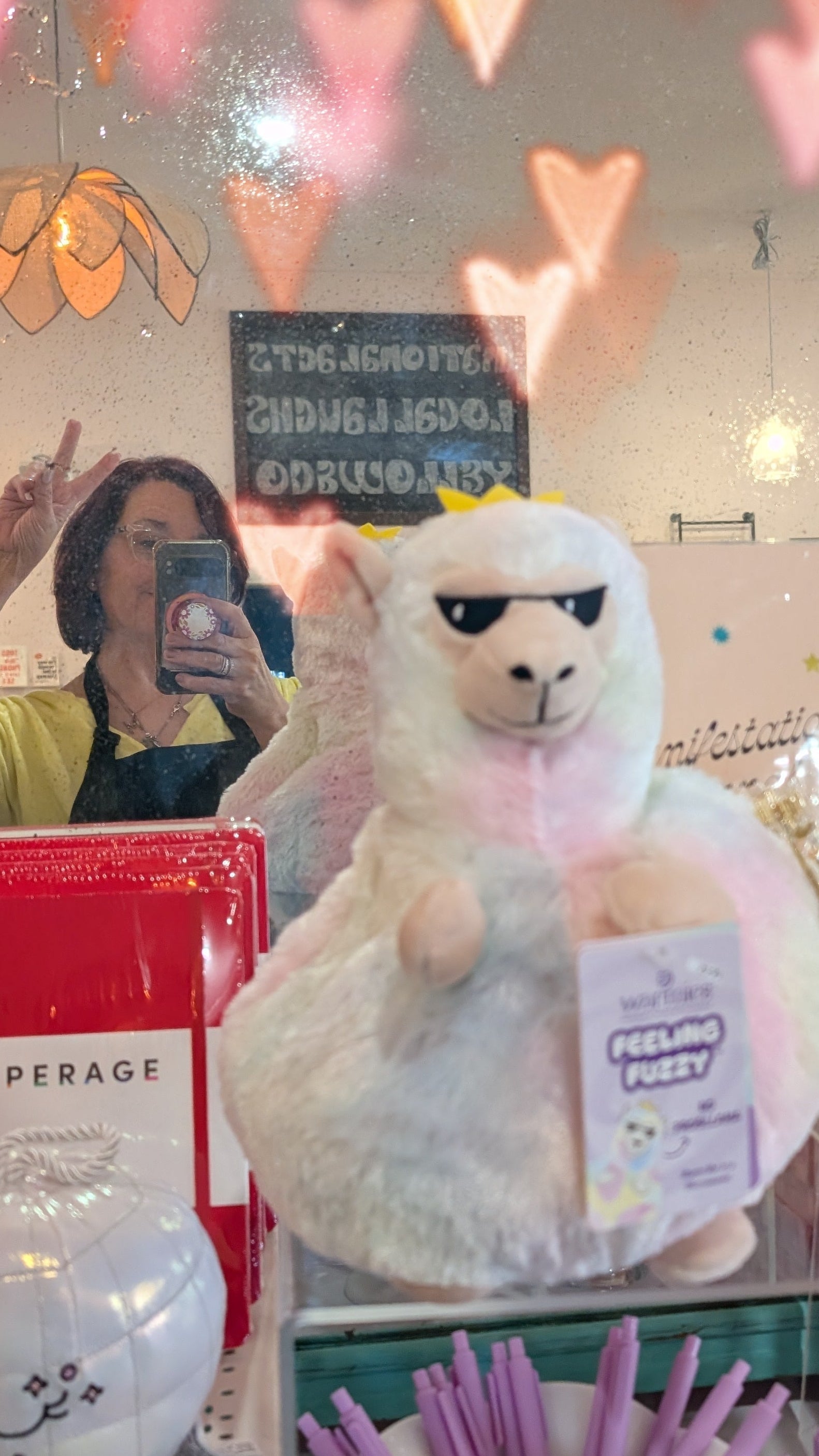 Person in a store holding a plush toy with heart-shaped lights in the background