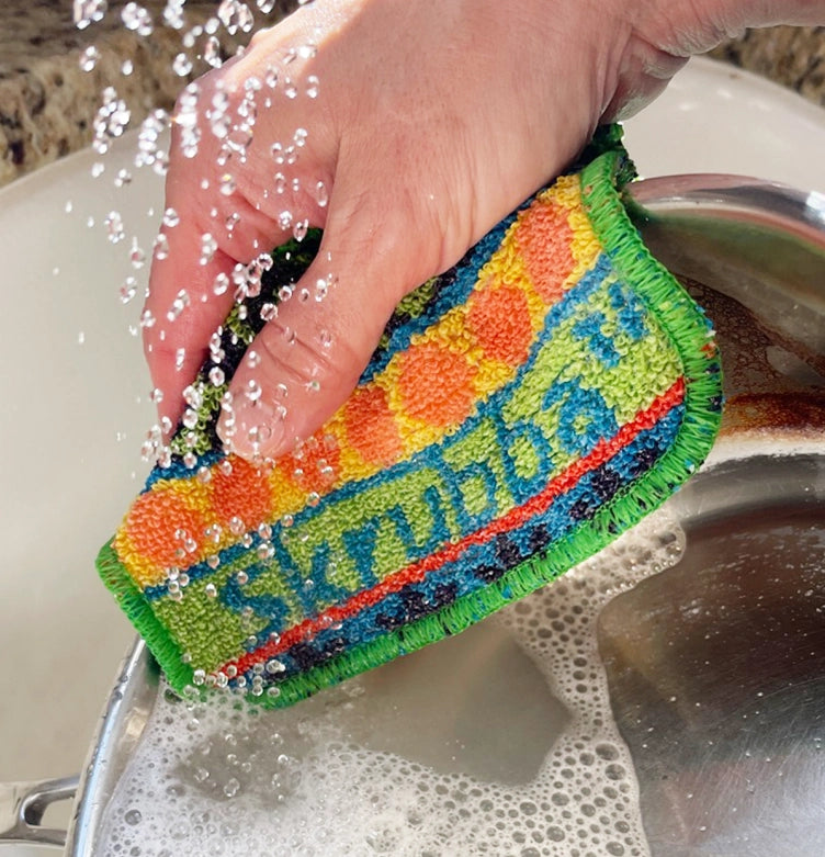 Colorful scrubber with colorful pattern being rinsed under running water
