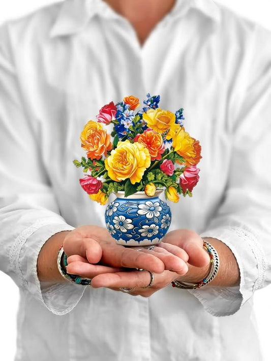 Person holding a small vase with colorful flowers against a white background