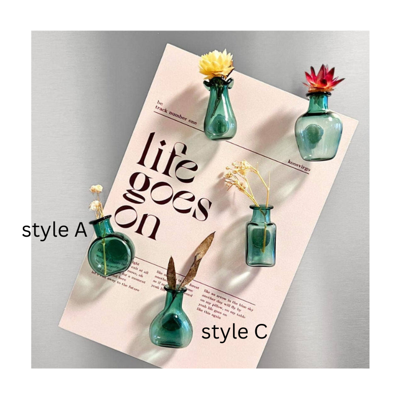 Four small teal glass vases with different shapes, arranged on a light pink magazine page against a gray background. The vases are shown with yellow, red, and brown dried floral accents, with text overlays reading 'style A', 'style C', and 'style B'.